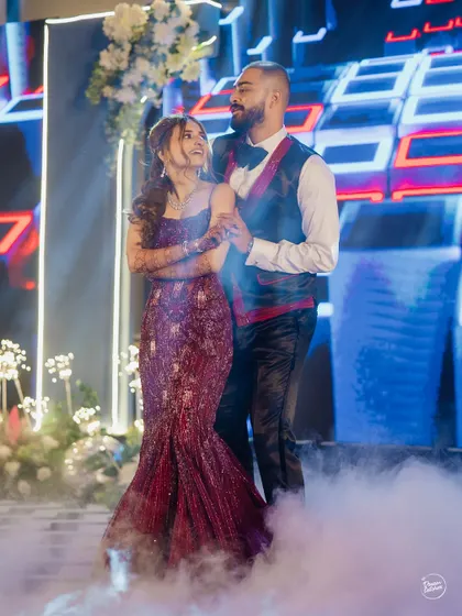 A sweet moment during their Sangeet dance, surrounded by a dreamy, smoky atmosphere.