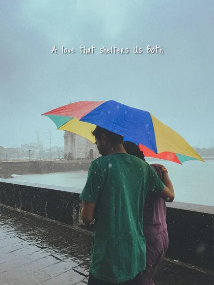 A love that shelters you both. A couple walks along the sea face with a colourful umbrella, a bright spot in the grey monsoon day.
