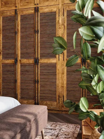 To evoke a year-round summer feeling, we designed this bedroom with tropical-inspired elements. Louvered wooden wardrobe doors, natural fiber lighting, and lush indoor plants create a warm, relaxed atmosphere reminiscent of a holiday escape.
