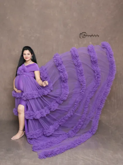 A full-length shot showcasing the dramatic train of a purple ruffled gown in our studio. The flying fabric creates a sense of movement and elegance.