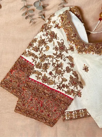 A white raw silk blouse hand-embroidered with zardozi, bringing a modern charm to any collection.