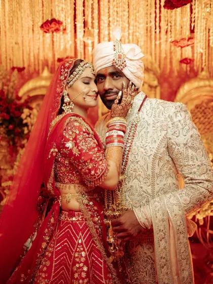 A tender moment between the bride and groom, framed by a backdrop of cascading florals and golden hues, capturing the essence of a royal love story.