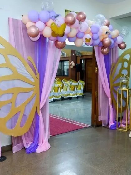 A grand entrance for a butterfly-themed party. We used large golden butterfly wing cutouts and draping fabrics to create a magical entryway for guests.