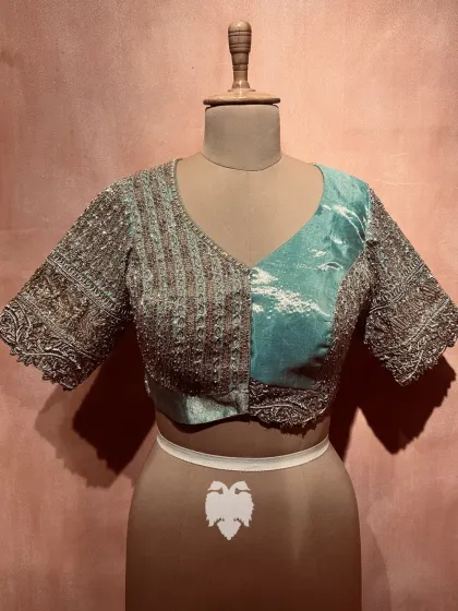 This ice blue tissue blouse features a striking asymmetric pattern, with one half in linear aari embroidery and the other with a soft sheen.