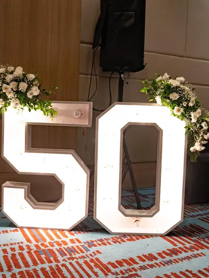 Large, light-up marquee numbers are a fantastic way to mark a milestone. For this 50th birthday, I adorned the numbers with simple white floral arrangements to add a touch of elegance.