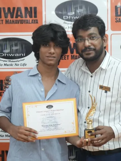 A teacher and his student pose with the award for his achievement.