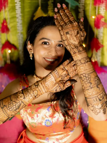A happy portrait of the bride, her hands adorned with classic peacock and floral mehendi.