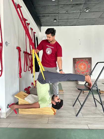 This supported inversion uses a bench, ropes, and a chair to create a therapeutic spinal extension. It is an advanced setup that provides deep decompression for the spine and is beneficial for experienced practitioners.