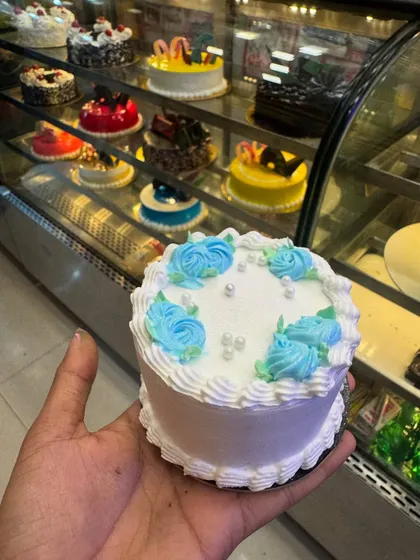 A white mini cake with delicate blue floral piping. It's a simple and pretty design, perfect for someone who loves classic and elegant aesthetics.