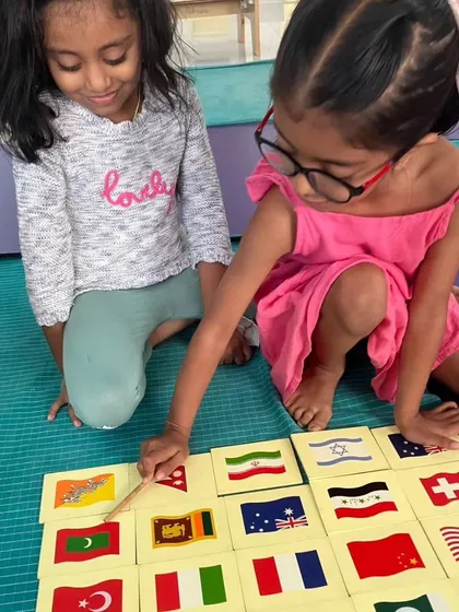 Two children work together to identify flags from around the world, a collaborative geography lesson.