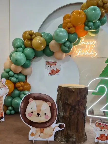 A different angle of our modern jungle theme, highlighting the balloon arch and the cute lion and fox characters.