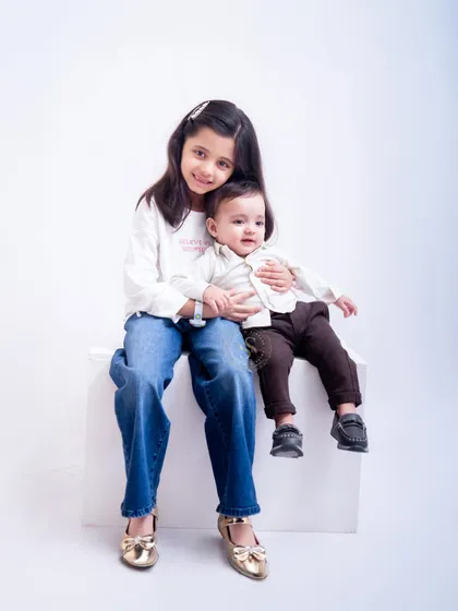 An older sister holds her baby brother in this simple and clean studio shot. These are the moments that become cherished memories.