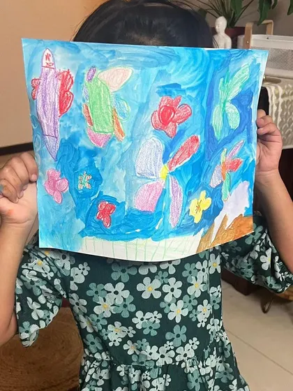 An online student proudly but shyly displays her vibrant aquarium painting. We create a safe space where even the quietest children feel comfortable sharing their art.