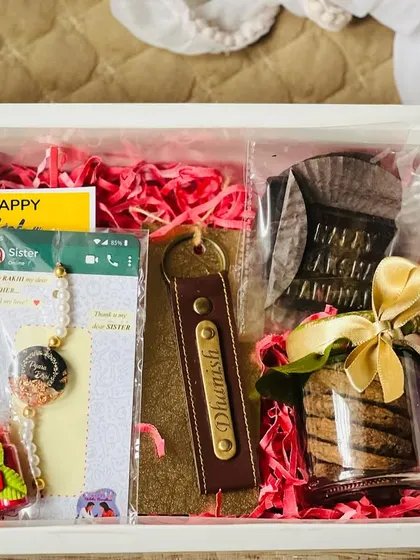 A close-up of the personalized Rakhi box, showing the custom keychain, photo rakhi, and homemade cookies.