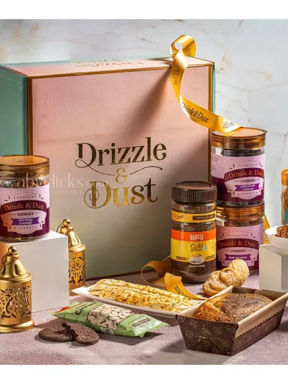 A premium gift box from Drizzle & Dust, elegantly styled with cookies, cakes, and decorative candles.