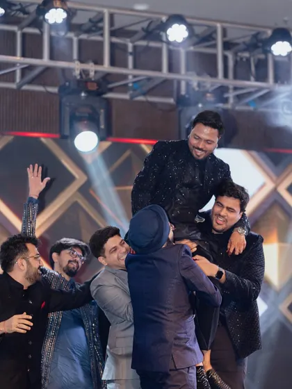 A classic 'groom on the shoulders' moment. These are the fun, unscripted celebrations that make a sangeet night so memorable for the groom and his friends.