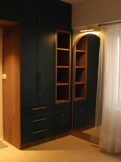 Embarking on a journey of craftsmanship and creativity. A stunning dark green and wood wardrobe with an arched mirror and open shelving.