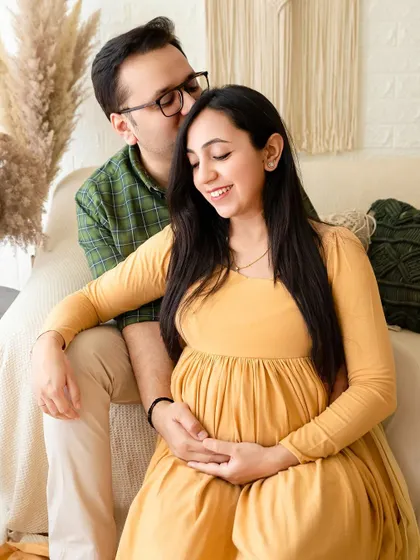 A loving embrace during a boho-style maternity photoshoot. This setup is perfect for couples who want a comfortable, lifestyle feel for their pregnancy portraits.