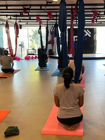 Students in Vajrasana, seen from behind, as they prepare for their aerial class.