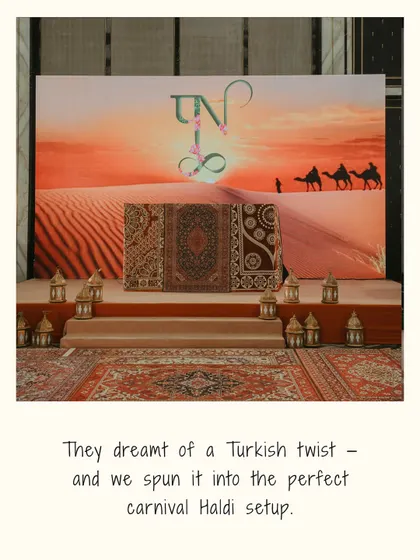 A photo backdrop for the Turkish Haldi, featuring a desert sunset scene, Persian rugs, and traditional lanterns, perfectly executing the couple's vision.