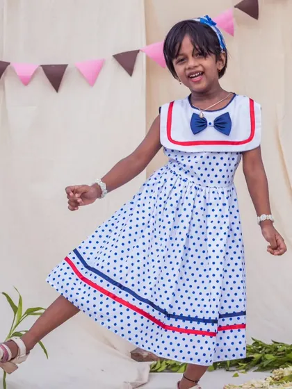 A joyful leap in a fun polka dot dress. This image captures the carefree spirit of childhood, and the dress is designed to move with her through every happy moment.