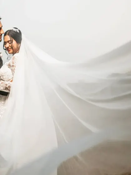 A tender moment with the groom kissing his bride's forehead, her veil sweeping across the frame. This shot is all about quiet affection and romance.