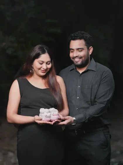 A couple sharing a happy moment while holding tiny baby shoes. This close-up shot during an outdoor session focuses on the small details that symbolize their growing family.