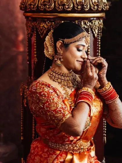 A candid moment of the bride adjusting her nose ring. The rich embroidery on her red blouse is a perfect match for her traditional silk saree.