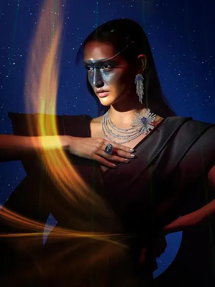 A shot from a cosmic-themed jewelry campaign, where the styling is designed to evoke the feeling of a supernova. The look combines a structured black gown with dramatic, celestial-inspired makeup and layers of statement diamond jewelry.