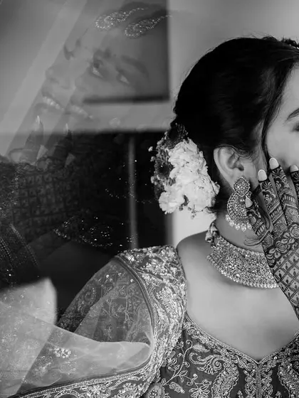 An artistic double exposure in black and white. This creative technique layers two moments together, showing the bride's joyful expression and her intricate henna details.