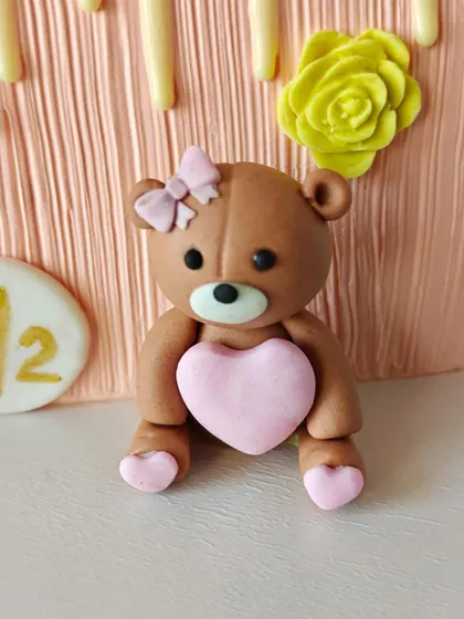 A close-up of the hand-sculpted fondant teddy bear, complete with a tiny pink bow and heart. It's these little details that make a cake extra special.