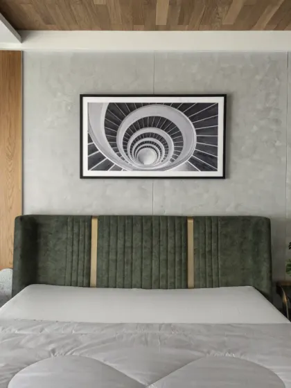 The first-floor bedroom in the Slender House, designed for the client's father, is positioned at the front to offer an extended balcony. The room is minimal, with a feature wall of wood and stone adding texture and warmth.