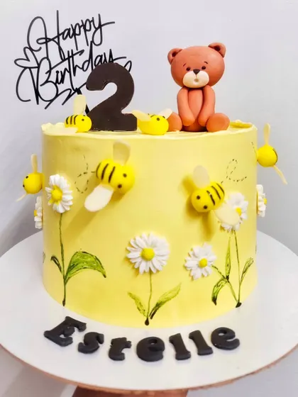 Honey bees and flowers for Estelle's 2nd birthday. This chocolate and biscoff cake is a sweet, summery design with hand-painted details.
