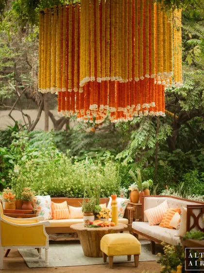 A lounge area at the 'Kesar Sehar' Haldi, featuring a tiered marigold chandelier. The design thoughtfully blended the traditional yellow Haldi theme with contemporary furniture and artisanal prints.