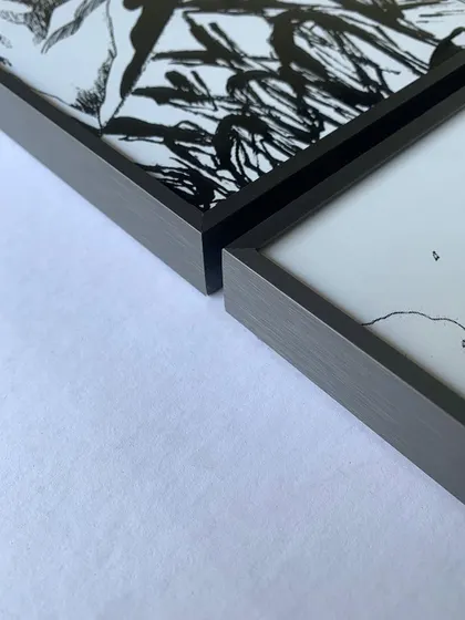 A close-up of the corner of our gray metal floater frames used for manga panels. The brushed metal finish adds a touch of sophistication to the black and white artwork.