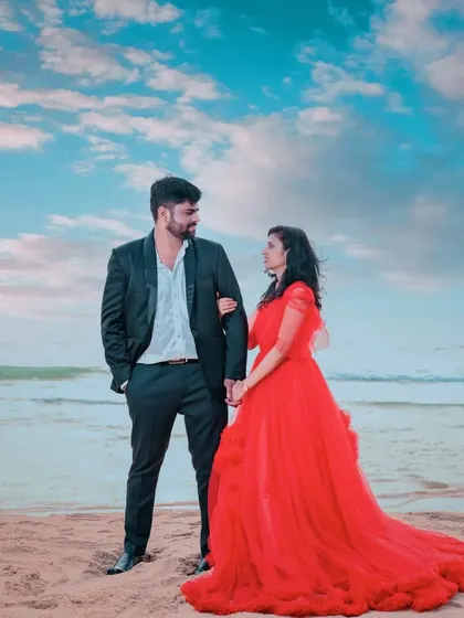 A stunning beach pre-wedding shoot. The red ruffle gown looks incredible against the blue sky and sea, creating a vibrant and romantic image.