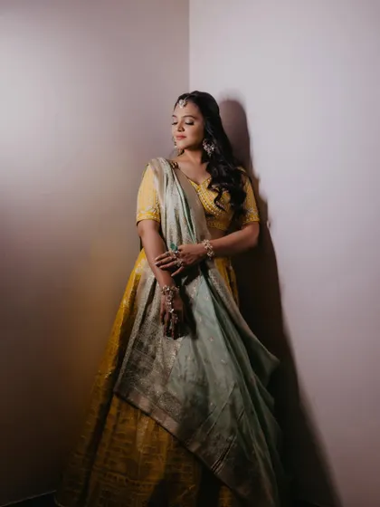 An artistic shot showing the bride in a moment of quiet reflection. The makeup looks stunning in the dramatic lighting.