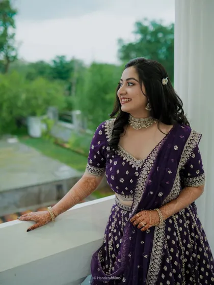 A beautiful candid of the bride in her purple reception lehenga. The makeup features a soft, dewy base and defined eyes, perfect for an evening event.