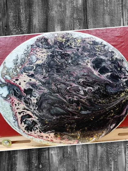 An abstract fluid art piece with dramatic black, white, and gold swirls. We teach different pouring techniques to achieve a variety of stunning abstract effects.