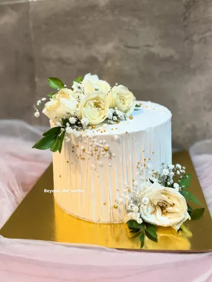 For those who love understated elegance, this minimalist cake is a perfect choice. I created a textured vertical line effect on the white buttercream and adorned it simply with fresh white roses and delicate baby's breath for a timeless look.