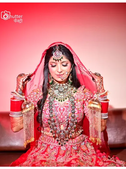 A beautiful portrait of the bride adjusting her veil, showcasing her magnificent jewelry and the rich colors of her lehenga.