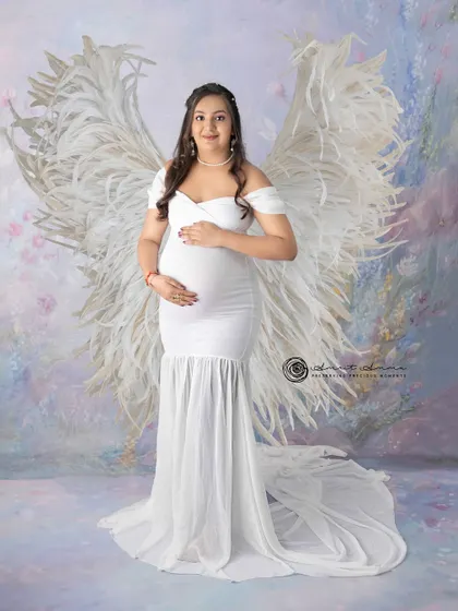 An angelic vision in white. The feather wings add a touch of the divine to this beautiful solo maternity portrait, celebrating the miracle of life.