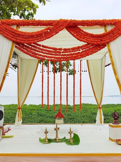 A beautiful beachside mandap decorated with orange marigolds and white fabric. The design is traditional yet feels light and airy, perfect for the location.