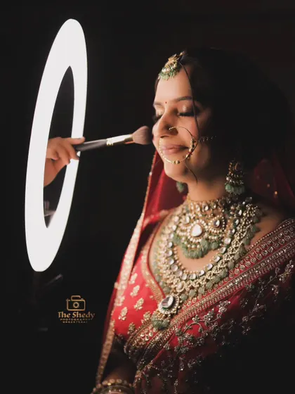 A creative shot of the bride getting a final touch-up. The ring light frames her face perfectly, creating a unique and modern portrait.