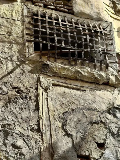 A close-up of a rusted metal grille and the surrounding decaying wall. This detail highlights the beauty in imperfection and the stories told by materials as they age.