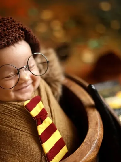 A heartwarming close up of a sleeping newborn, peacefully dreaming of magic. The tiny glasses and Gryffindor scarf are perfect details for this popular themed photoshoot.
