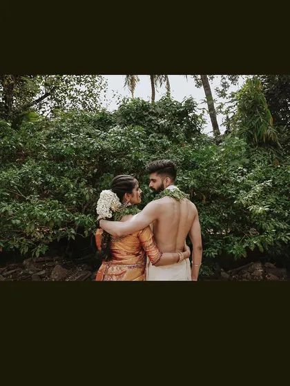 A romantic shot of a couple from behind, embracing as they look out at the trees.