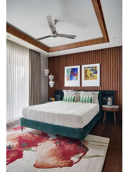 A wider view of the master bedroom, where a floral rug adds a splash of color and softness to the wooden flooring.
