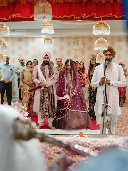 A wide shot of a Sikh wedding ceremony in a Gurdwara. We capture the serene atmosphere and the traditional rituals with a sense of reverence.
