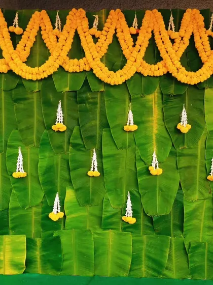 For a more natural and traditional look, I designed this backdrop using fresh banana leaves. It's adorned with garlands of marigold and jasmine flowers, perfect for eco-friendly poojas, baby showers, or other ceremonies.